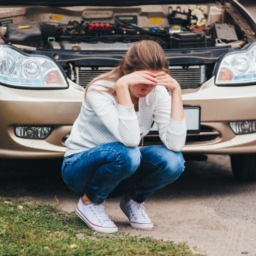 extended car warranty services woman upset next to broken car with open hood